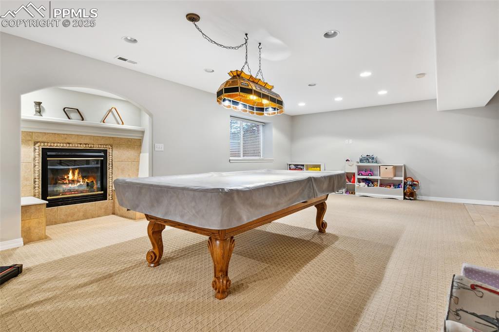Image 31 of 47: Rec room featuring carpet floors, pool table, a tiled fireplace, and recess