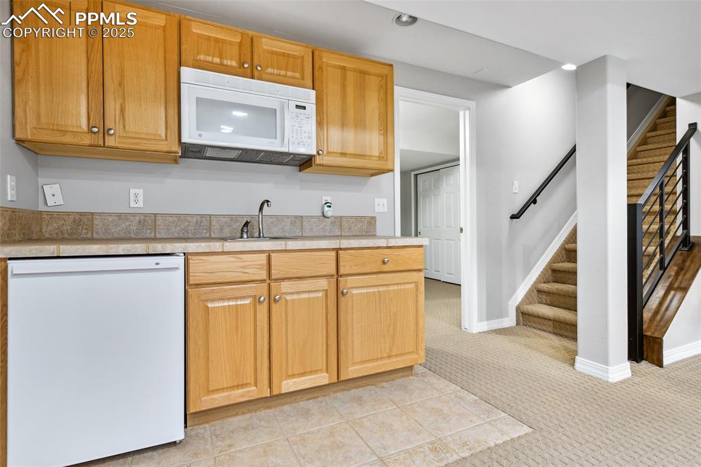 Image 34 of 47: Kitchen featuring white appliances, light countertops, and light carpet