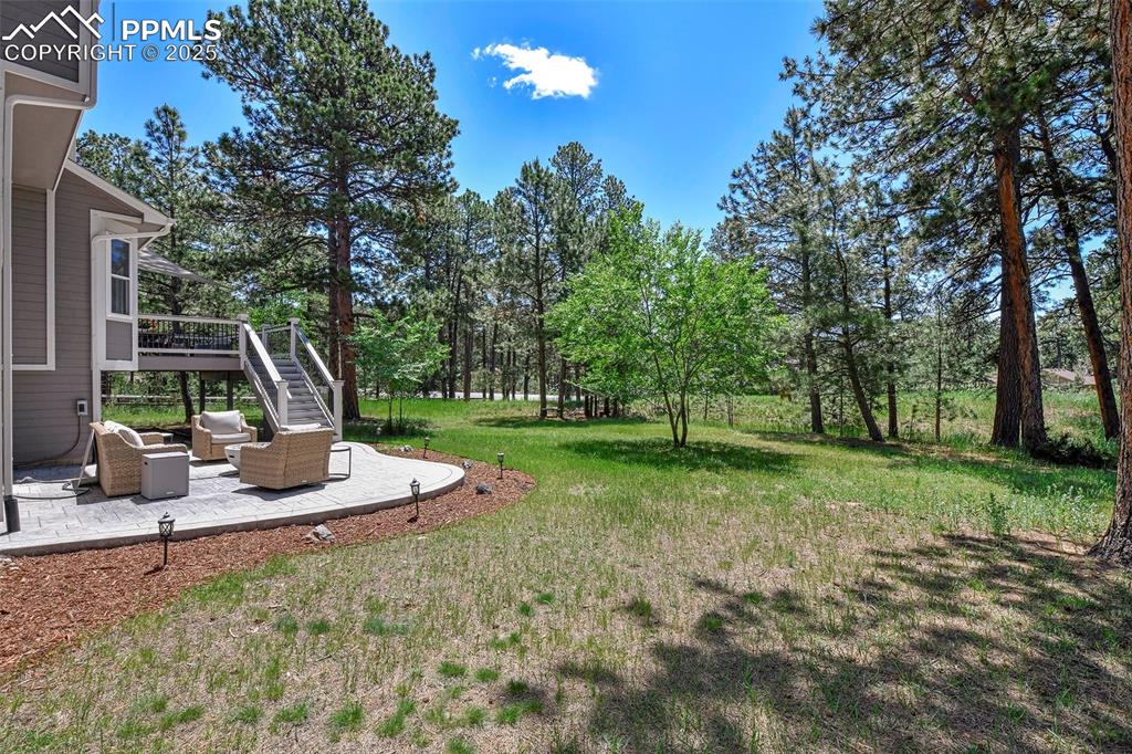 Image 46 of 47: View of grassy yard featuring a patio, stairs, an outdoor hangout area, and