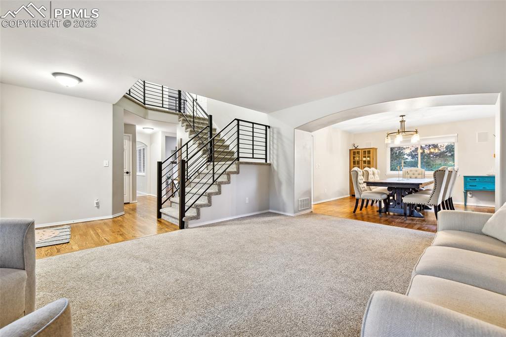 Image 7 of 47: Carpeted living area featuring arched walkways, stairway, wood finished flo