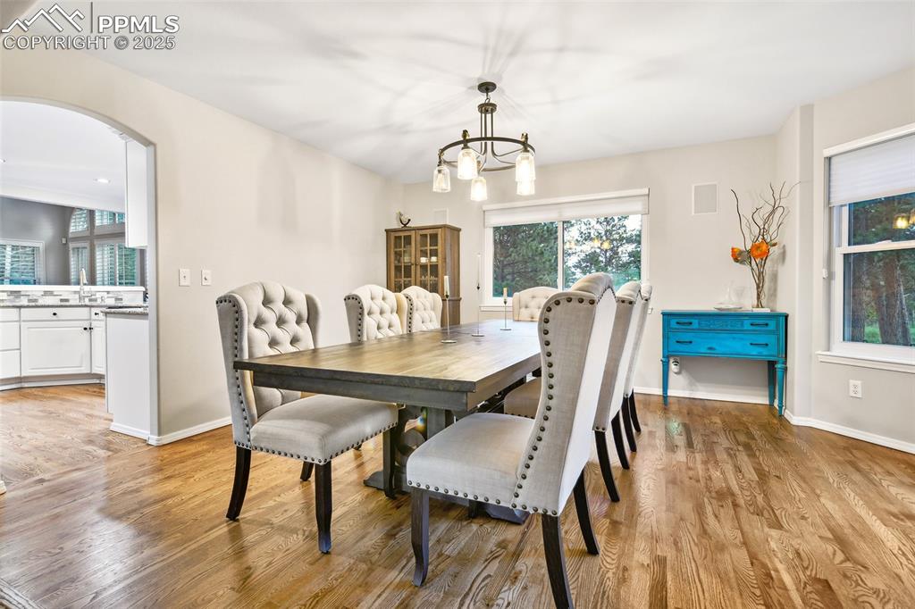 Image 8 of 47: Dining area with light wood finished floors, a chandelier, and arched walkw