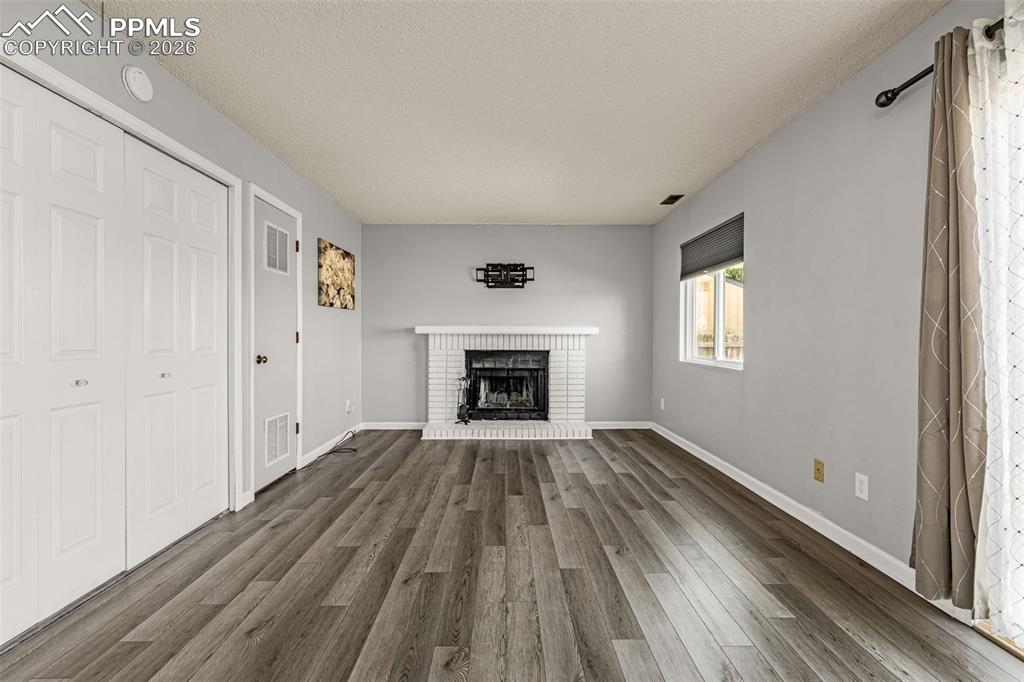 Image 11 of 30: Unfurnished living room featuring a textured ceiling, dark wood-style floor