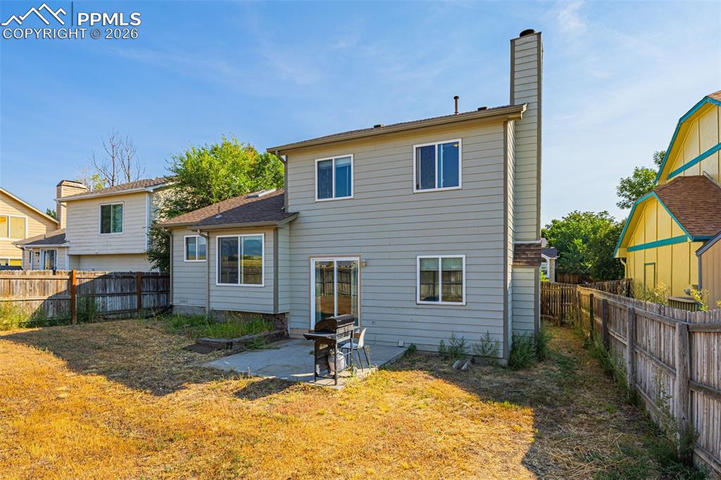 Image 23 of 30: Back of property with a patio, a fenced backyard, and a chimney