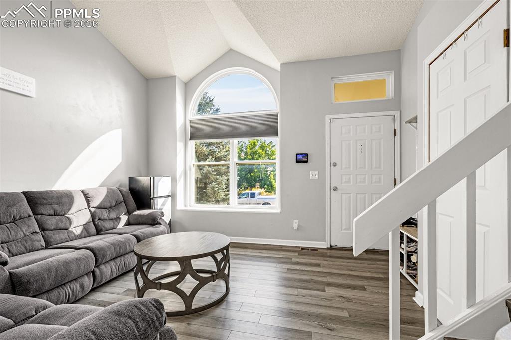 Image 5 of 30: Living area with a textured ceiling, wood finished floors, and lofted ceili