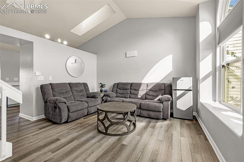 Image 6 of 30: Living area featuring vaulted ceiling, a skylight, and light wood finished 