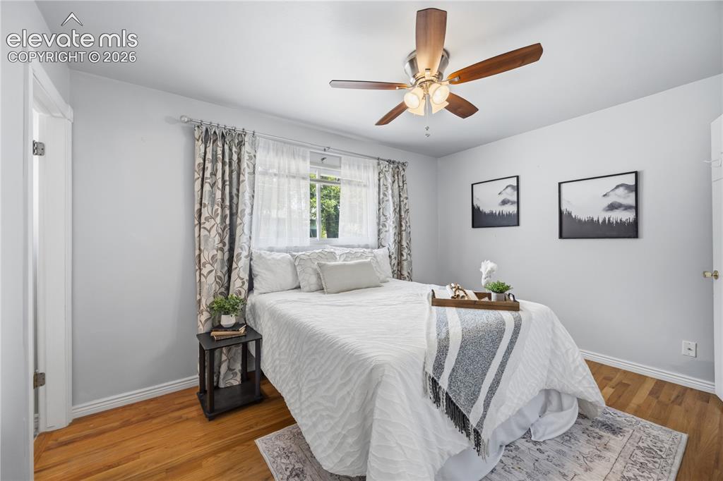 Image 10 of 25: Primary Bedroom featuring wood-finish flooring, a ceiling fan with a light 