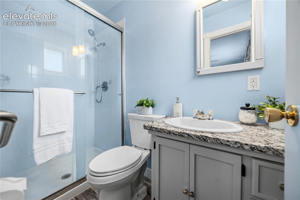 Image 12 of 25: Bathroom featuring a glass-enclosed shower, white toilet, single vanity wit