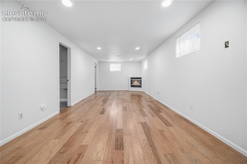Image 13 of 25: Spacious family room featuring wood-finish flooring and a cozy corner gas f