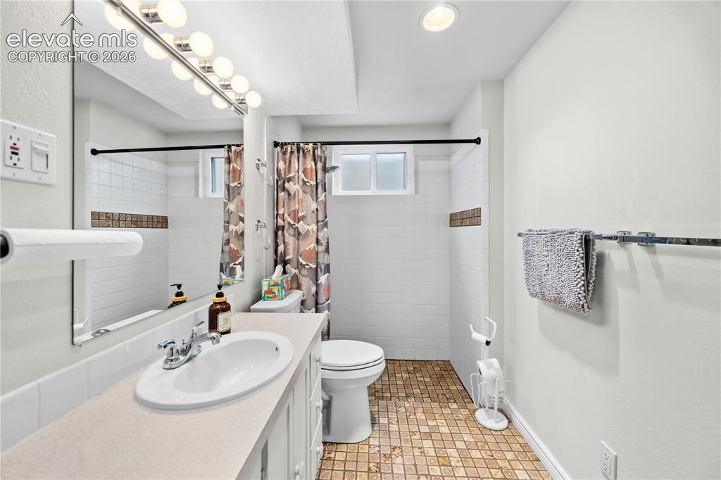 Image 14 of 25: Bathroom featuring a large vanity with an integrated sink, a large wall mir