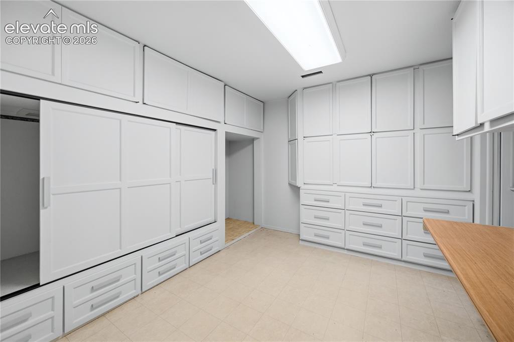 Image 16 of 25: Dedicated storage room featuring extensive built-in cabinetry, sliding clos