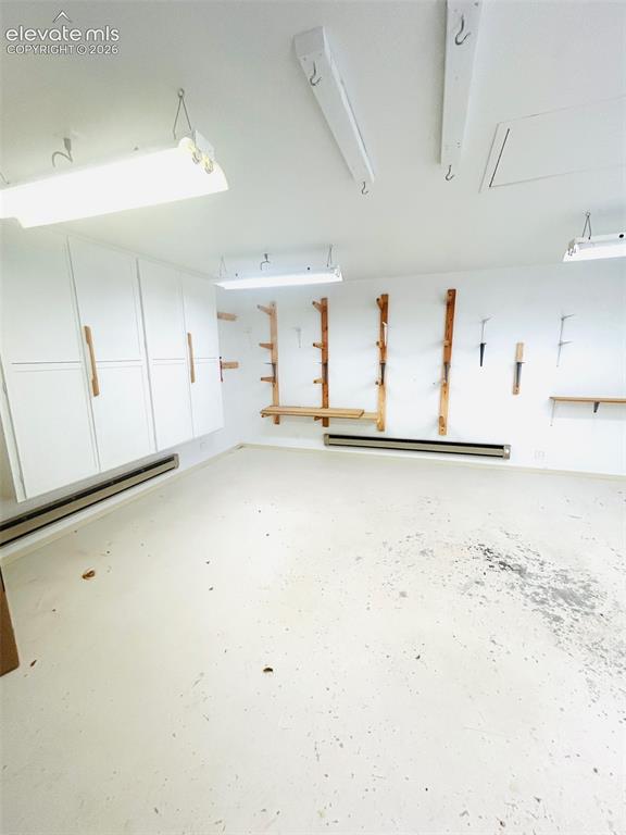 Image 19 of 25: Heated workshop/hobby room featuring built-in cabinetry, wall-mounted stora