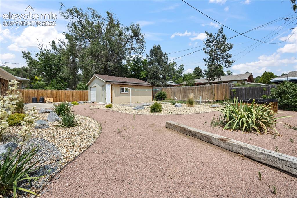 Image 20 of 25: Expansive xeriscaped backyard featuring a detached garage, privacy fencing,