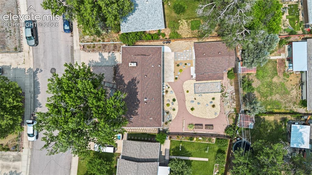Image 22 of 25: Expansive property with a brown shingle roof, xeriscaped yard, red brick pa