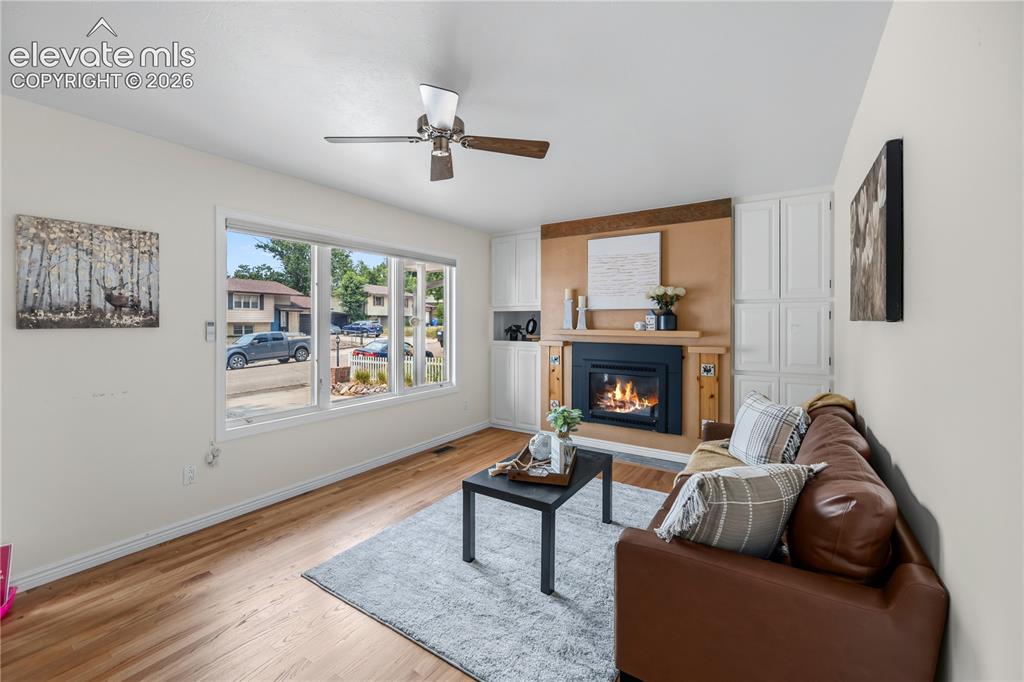 Image 3 of 25: Living space featuring a fireplace with a wood mantle, built-in cabinetry, 