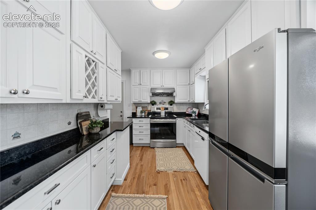 Image 5 of 25: Galley kitchen featuring abundant white cabinetry with silver hardware, dar