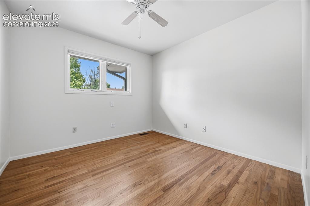 Image 7 of 25: Hardwood flooring throughout featuring white walls, a white ceiling fan, an