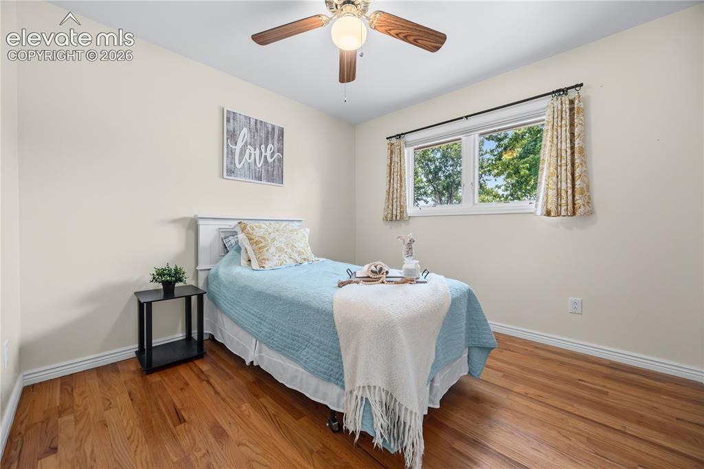 Image 8 of 25: Room featuring wood-finish flooring, a white window frame, and a ceiling fa