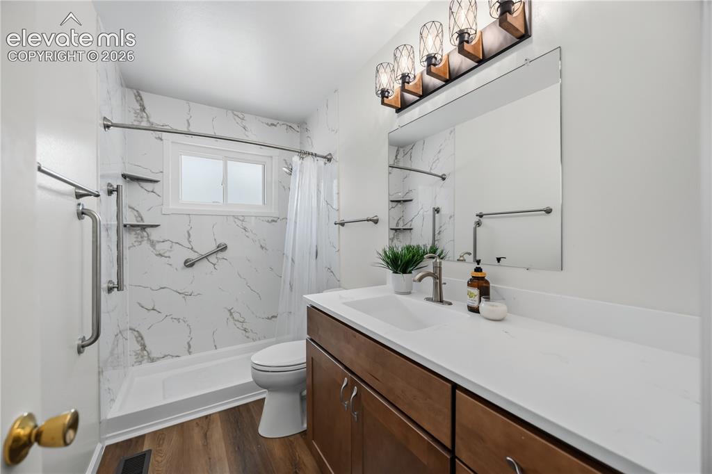 Image 9 of 25: Bathroom featuring a walk-in shower with grab bars and marble-look wall pan