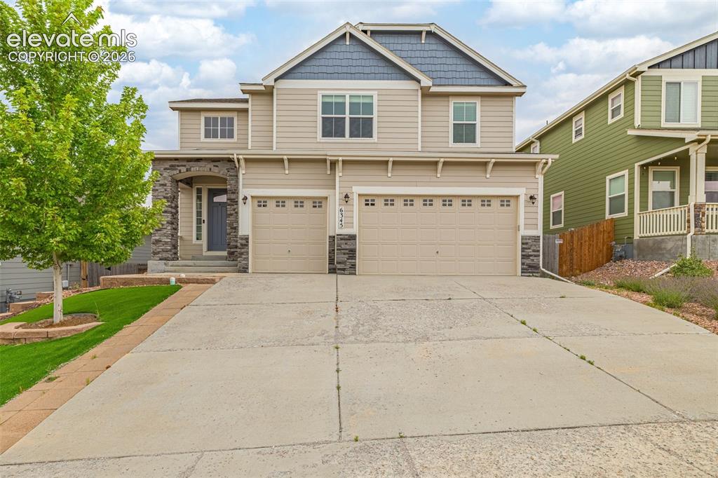 Caption: Two-story residence featuring a two-car garage, stone accents, and a covered entry