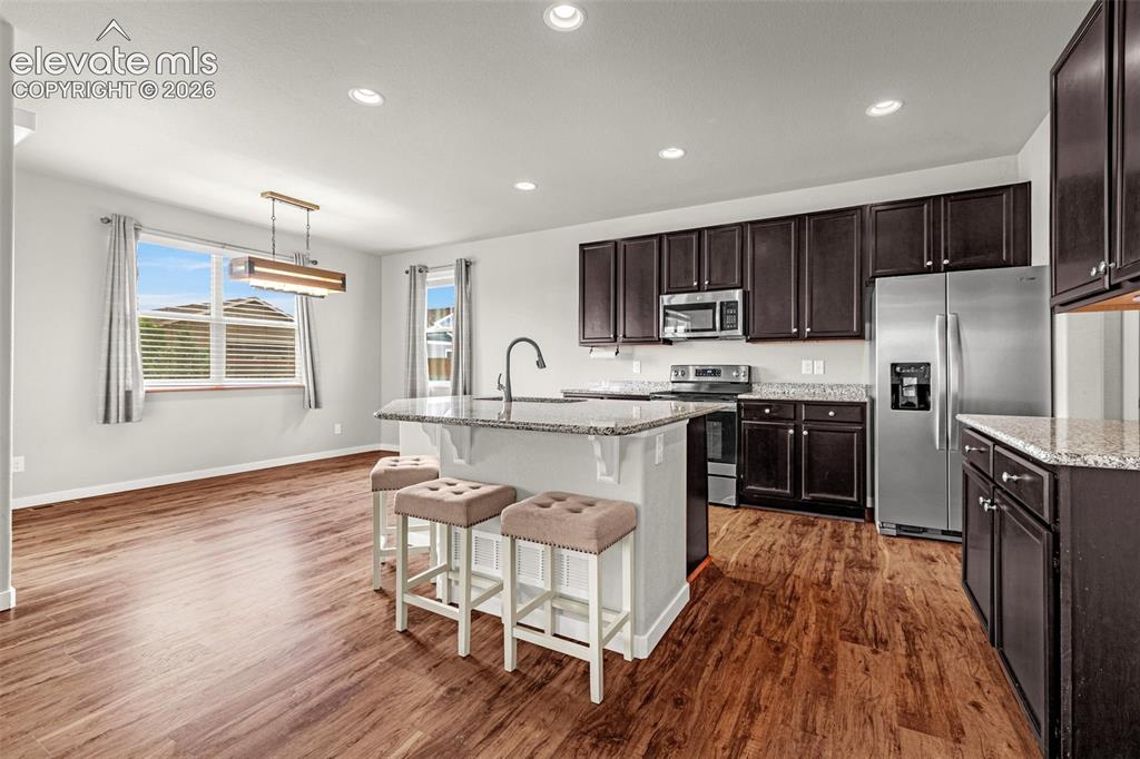 Image 11 of 44: Kitchen featuring dark wood-finish cabinetry, stainless steel appliances, a