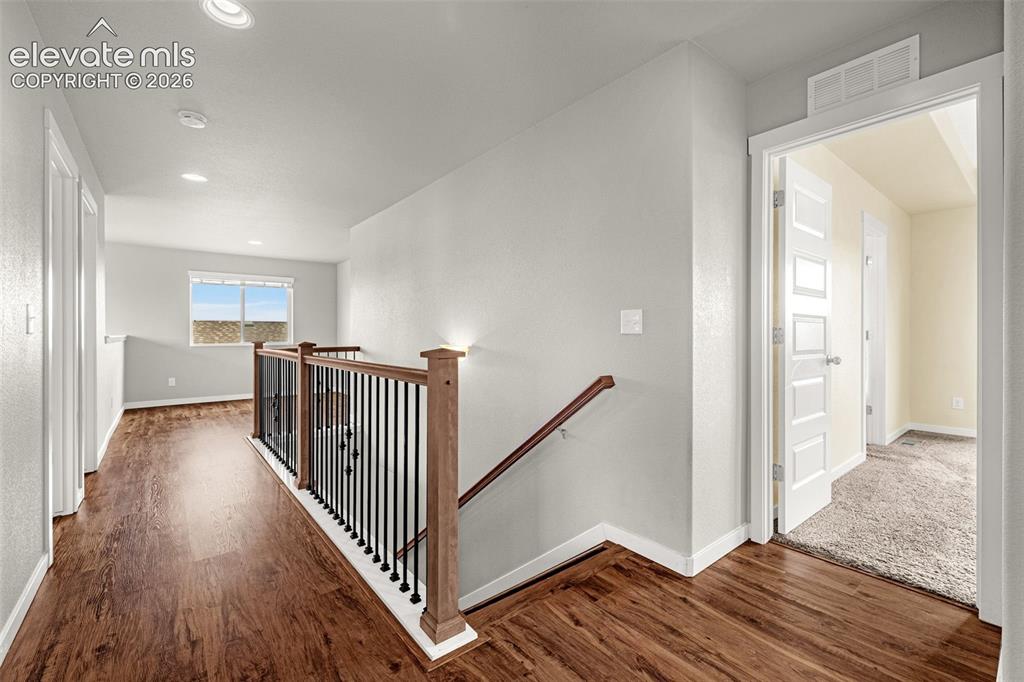 Image 13 of 44: Wood-finish flooring, staircase with dark metal balusters and wood newel po