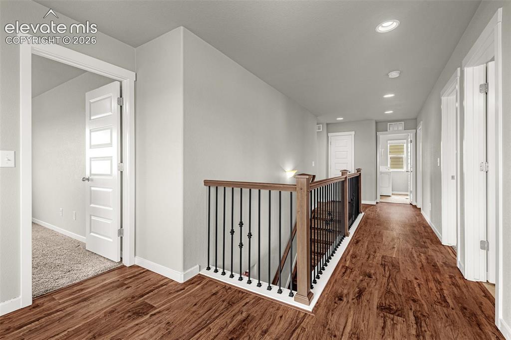 Image 14 of 44: Wood-finish flooring, staircase with wood handrail and wrought iron baluste