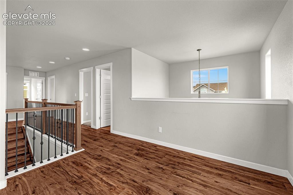 Image 15 of 44: Upper landing featuring wood-finish flooring, white walls, and a wrought ir