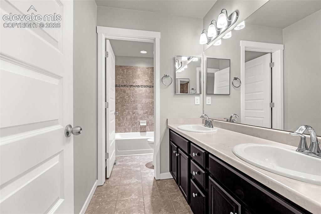 Image 18 of 44: Dual vanity with undermount sinks, chrome fixtures, and a spacious mirror