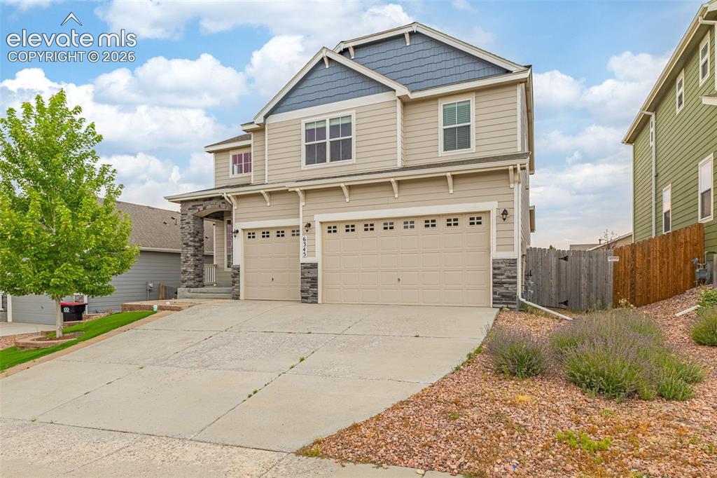 Image 2 of 44: Two-story residence featuring a two-car garage, stone column accents, neutr