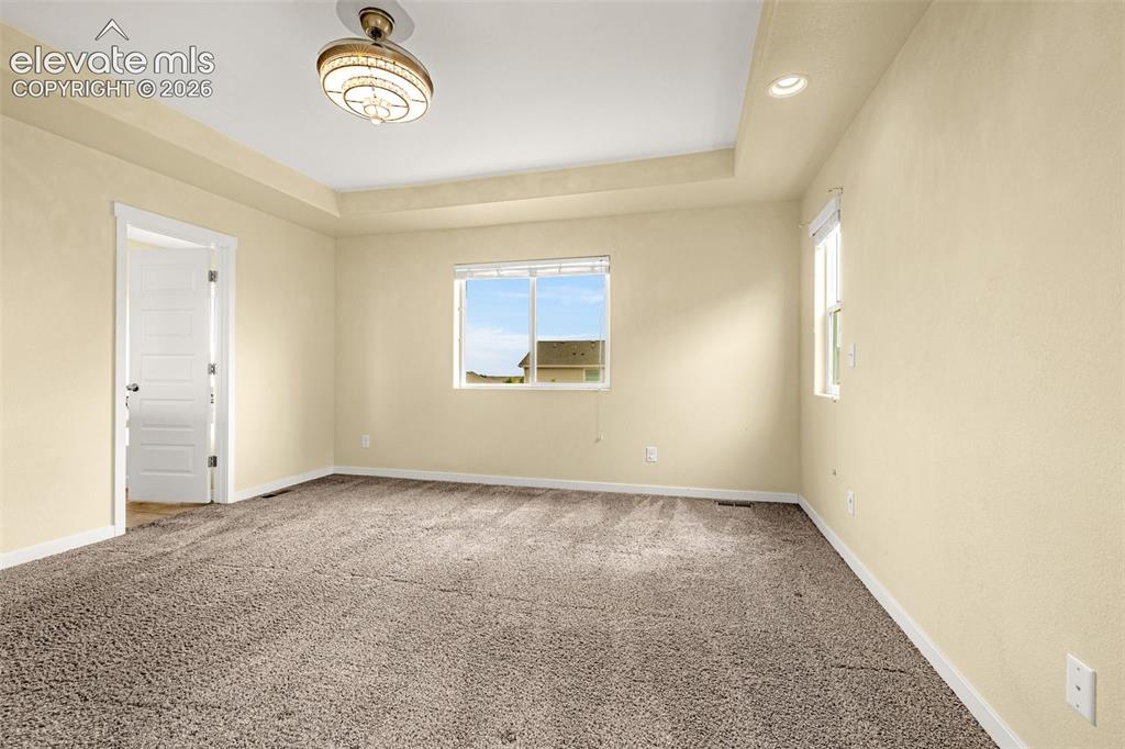 Image 25 of 44: Tray ceiling with recessed lighting and a central ceiling fixture, wall-to-