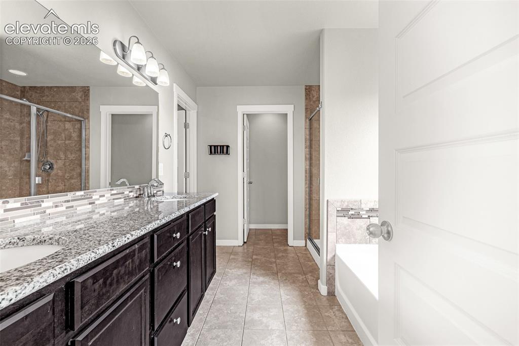 Image 26 of 44: Dual vanity with granite countertop and dark wood-finish cabinetry