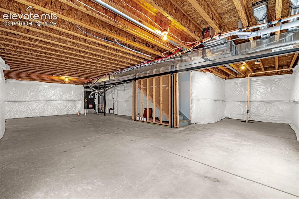 Image 29 of 44: Unfinished basement with concrete flooring and exposed ceiling joists