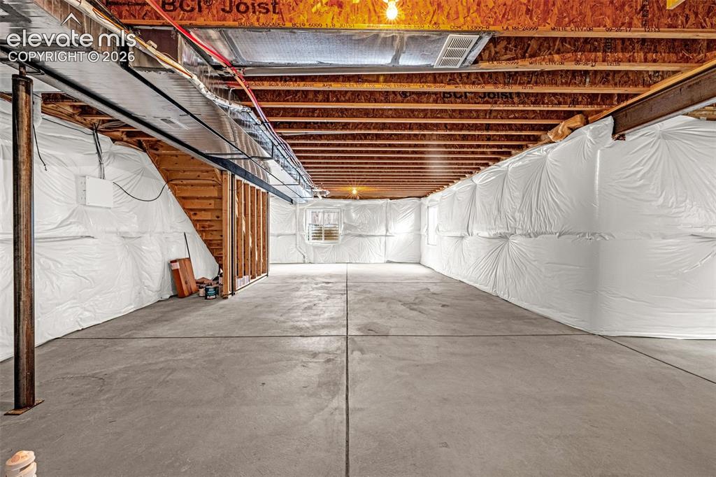 Image 30 of 44: Unfinished basement featuring exposed wood joists, concrete flooring, and a