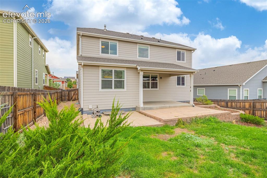 Image 34 of 44: Two-story exterior with light-toned siding, covered concrete patio, and an 
