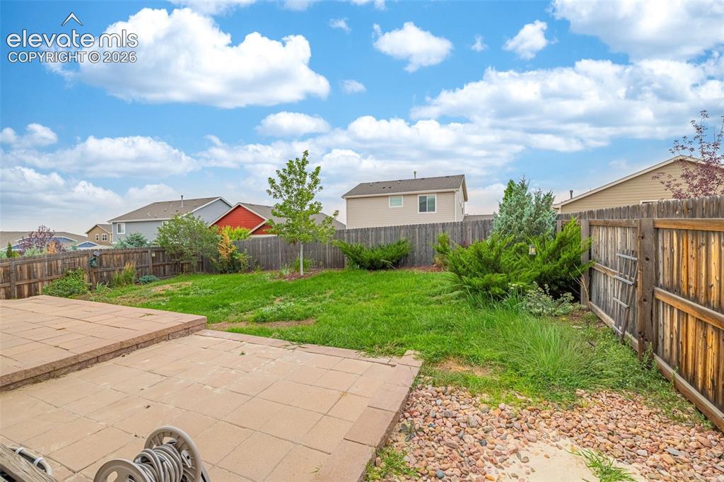 Image 35 of 44: Expansive backyard featuring a stone paver patio, a wood privacy fence, and