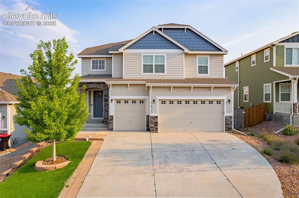 Image 36 of 44: Two-story exterior with a two-car garage, stone accents, and a covered entr
