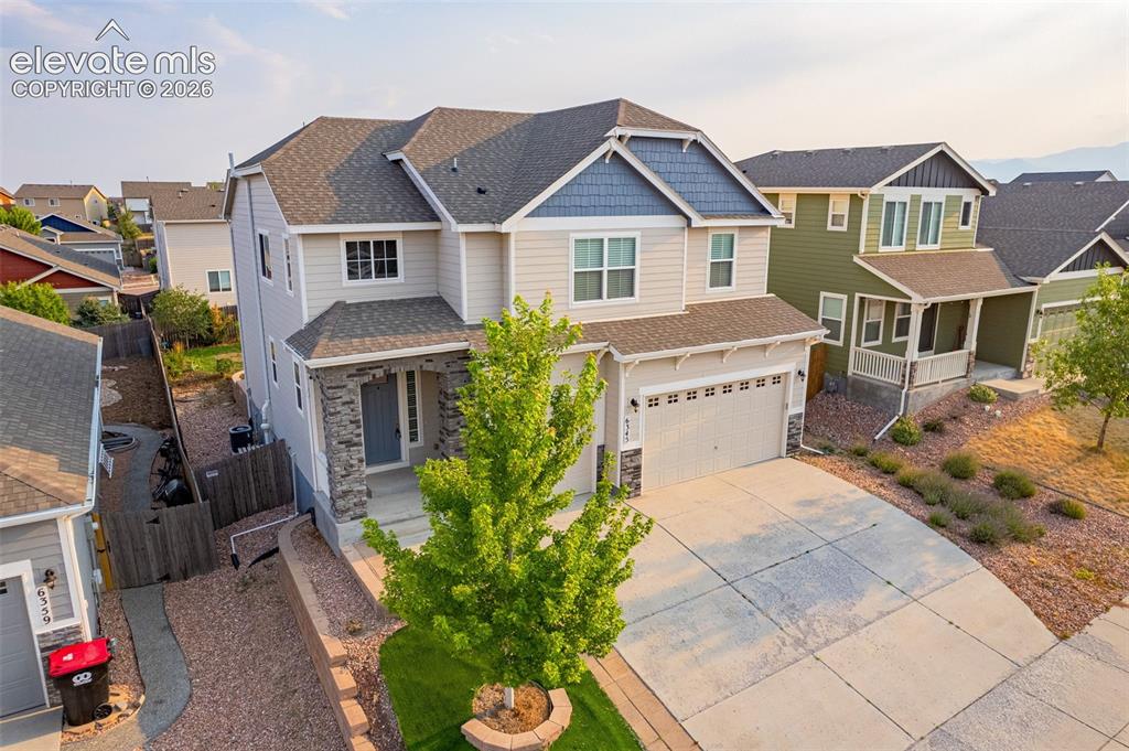 Image 38 of 44: Two-story exterior with a covered entry, stone facade accents, and an attac