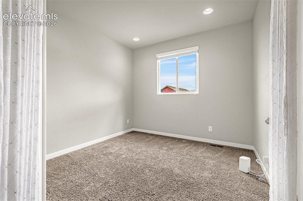 Image 6 of 44: Neutral wall paint, recessed ceiling lighting, light-filtering window shade