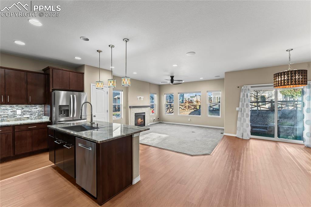 Image 15 of 45: Kitchen with pendant lighting, open floor plan, dark stone countertops, an 