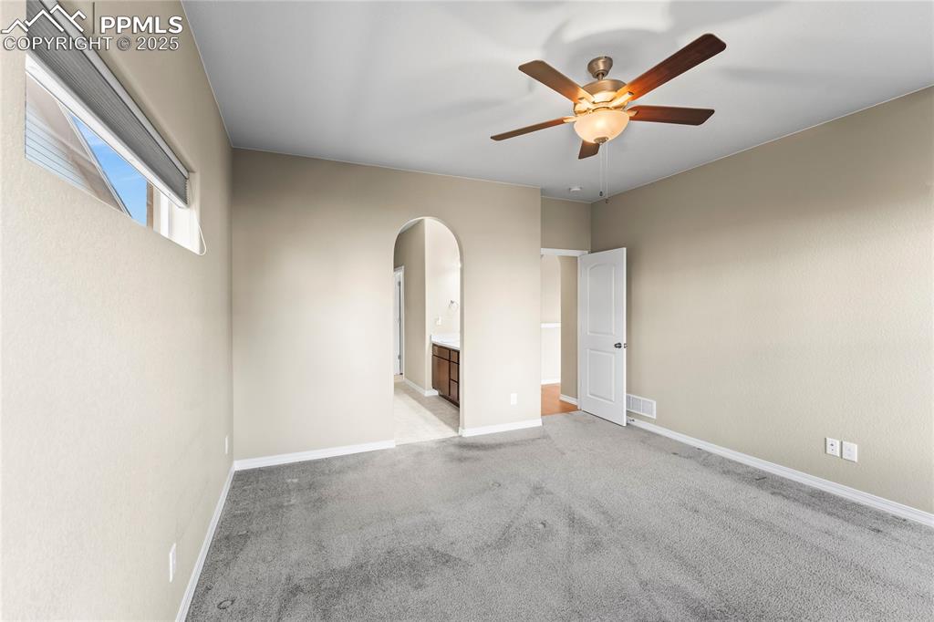 Image 19 of 45: Spare room with light colored carpet, arched walkways, and ceiling fan