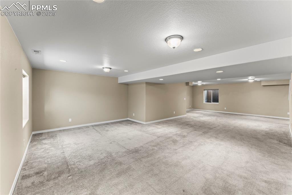 Image 27 of 45: Basement with light colored carpet, recessed lighting, and a textured ceili