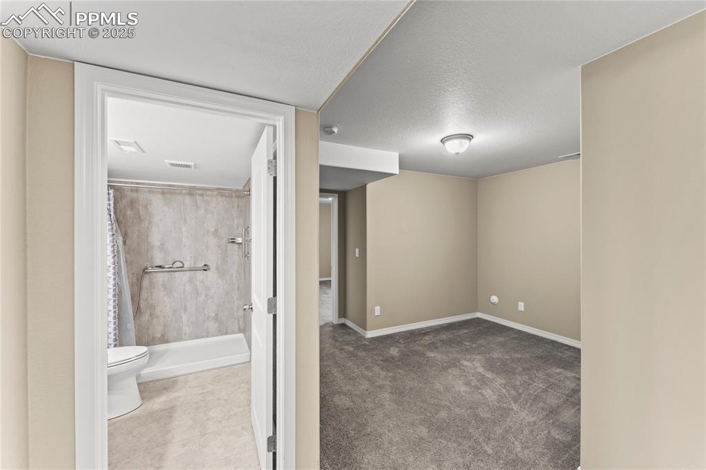 Image 28 of 45: Basement featuring a textured ceiling and carpet