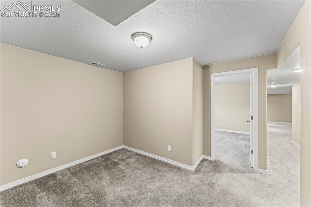 Image 29 of 45: Carpeted empty room with a textured ceiling and baseboards