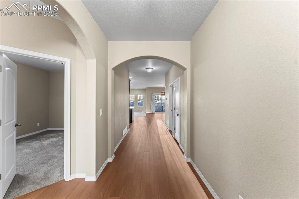 Image 3 of 45: Hallway featuring arched walkways and wood finished floors