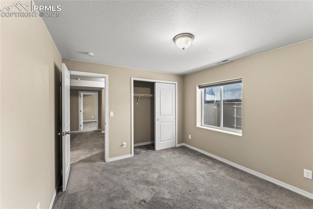 Image 33 of 45: Unfurnished bedroom featuring carpet flooring, a closet, and a textured cei