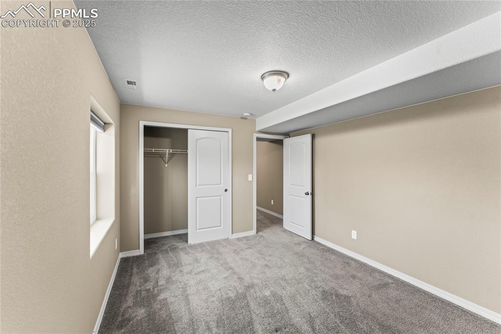 Image 35 of 45: Unfurnished bedroom featuring carpet floors, a closet, and a textured ceili
