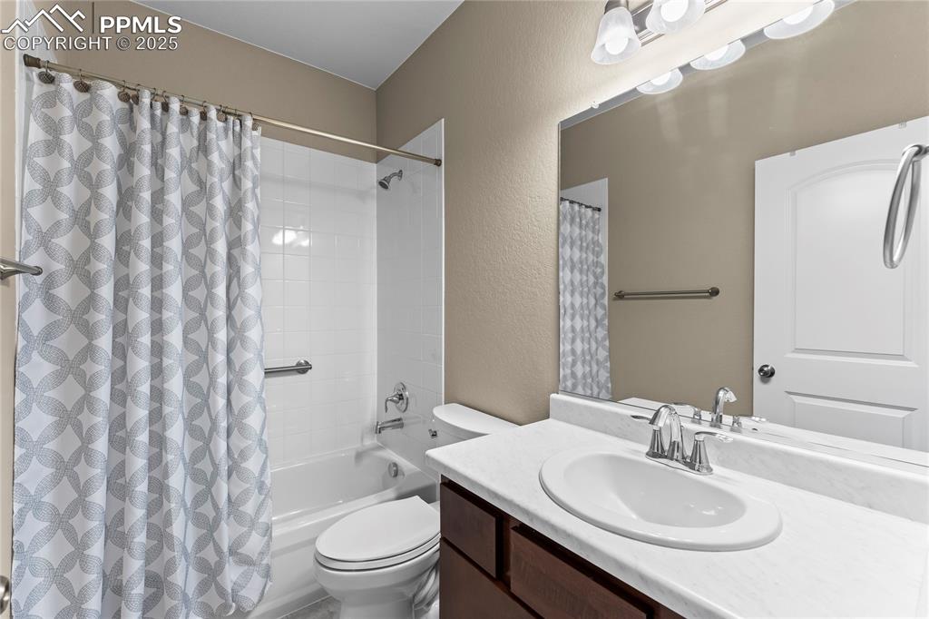 Image 7 of 45: Bathroom featuring a textured wall, vanity, and shower / bath combination w