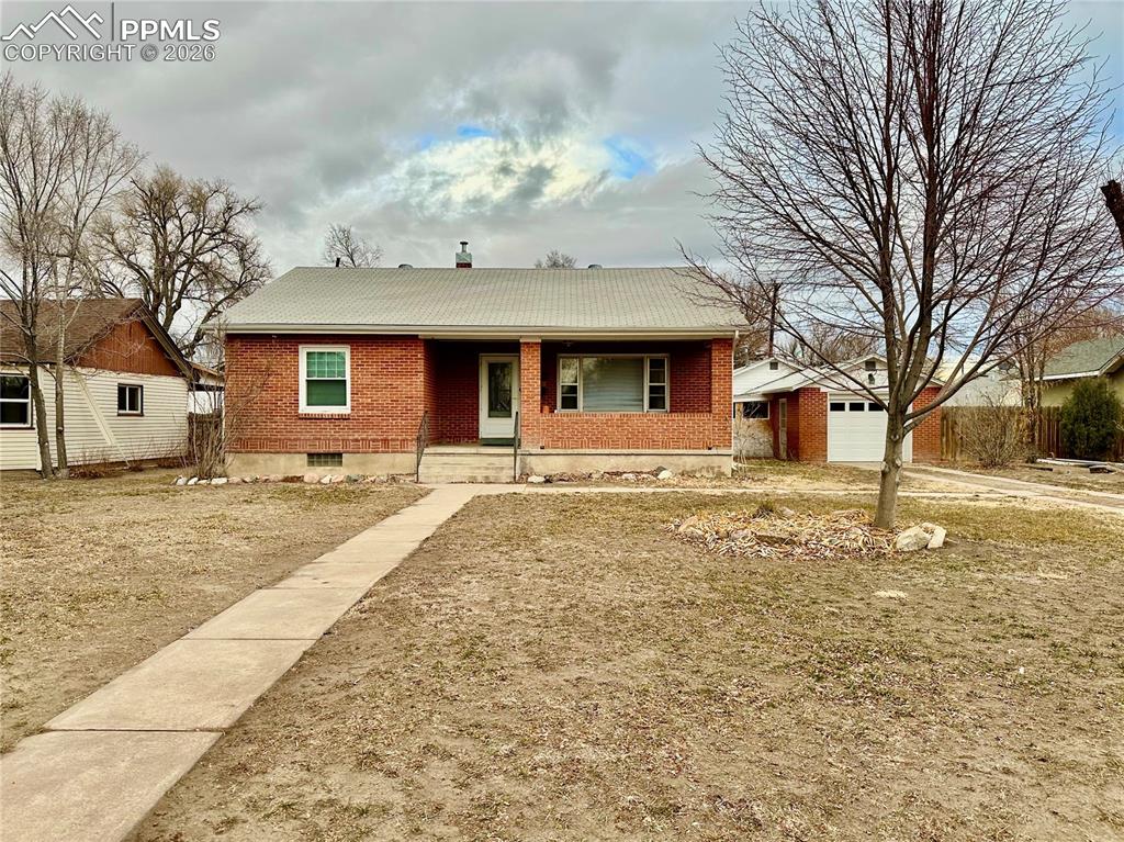 Caption: Ranch-style house with brick siding, a porch, a garage, and an outdoor structure