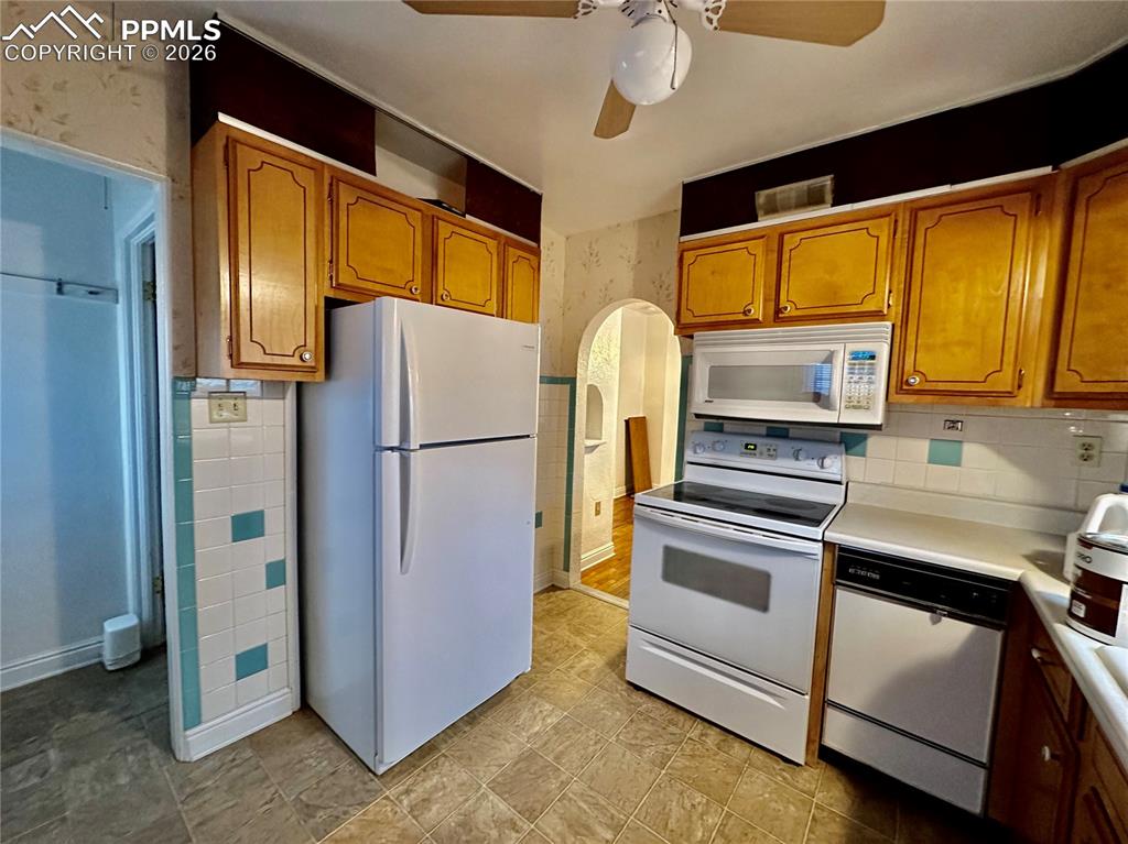 Image 10 of 28: Kitchen featuring white appliances, arched walkways, light countertops, bro
