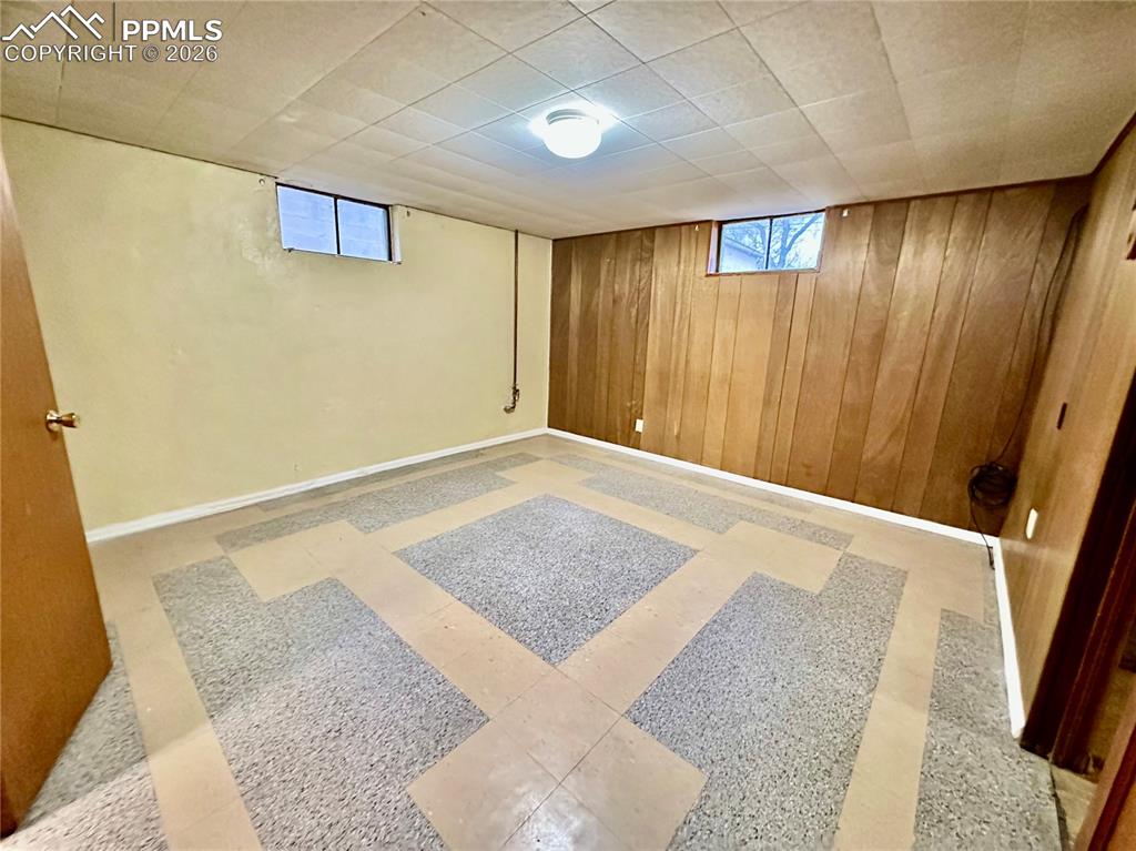 Image 24 of 28: Below grade area with light floors, plenty of natural light, and wooden wal